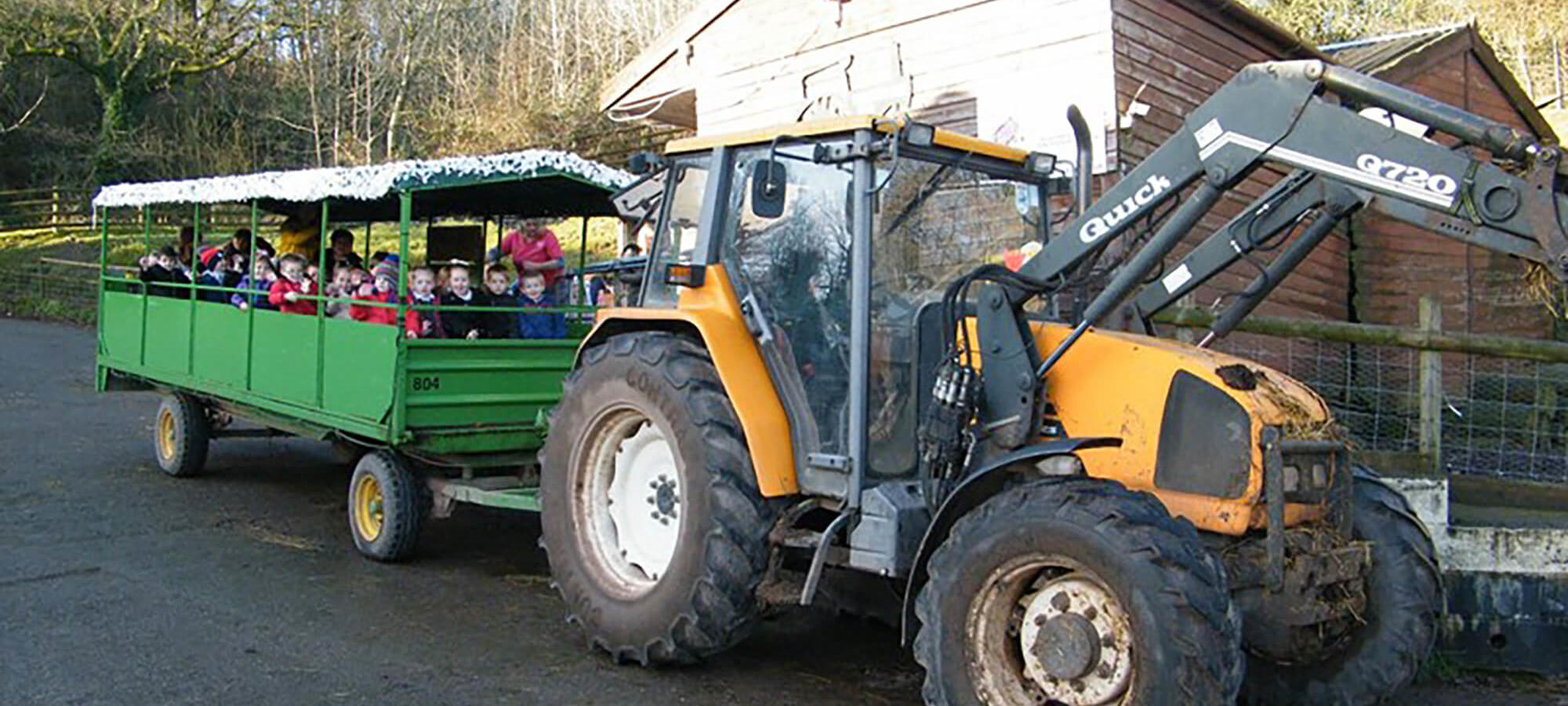 A yellow and black tractor pulling a green trailer