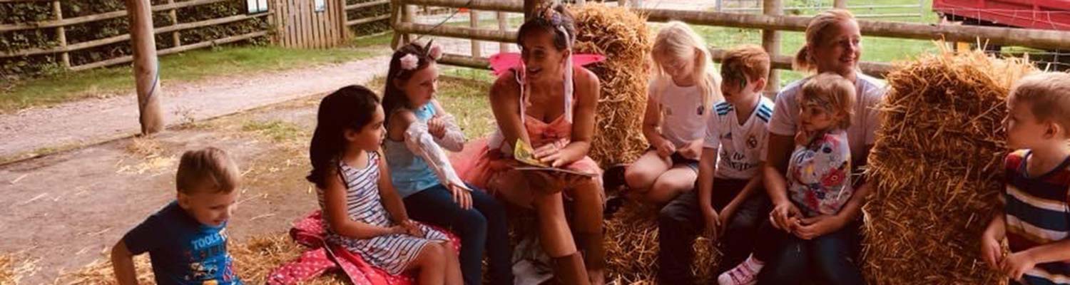 Children sitting on hay bales listening to a story