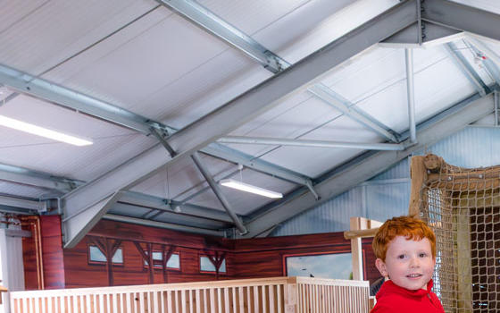 Young boy sitting on a wooden tractor in the indoor adventure play
