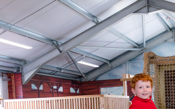 Young boy sitting on a wooden tractor in the indoor adventure play