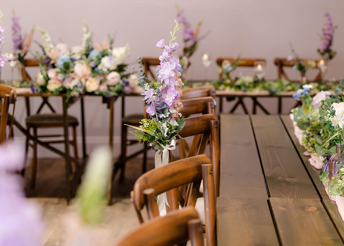 A long dining table decorated with an array of flowers and greenery, enhancing the ambiance of the setting